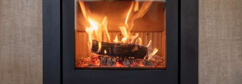Ein brennendes Holzscheit in einem modernen Kamin mit schwarzem Rahmen.